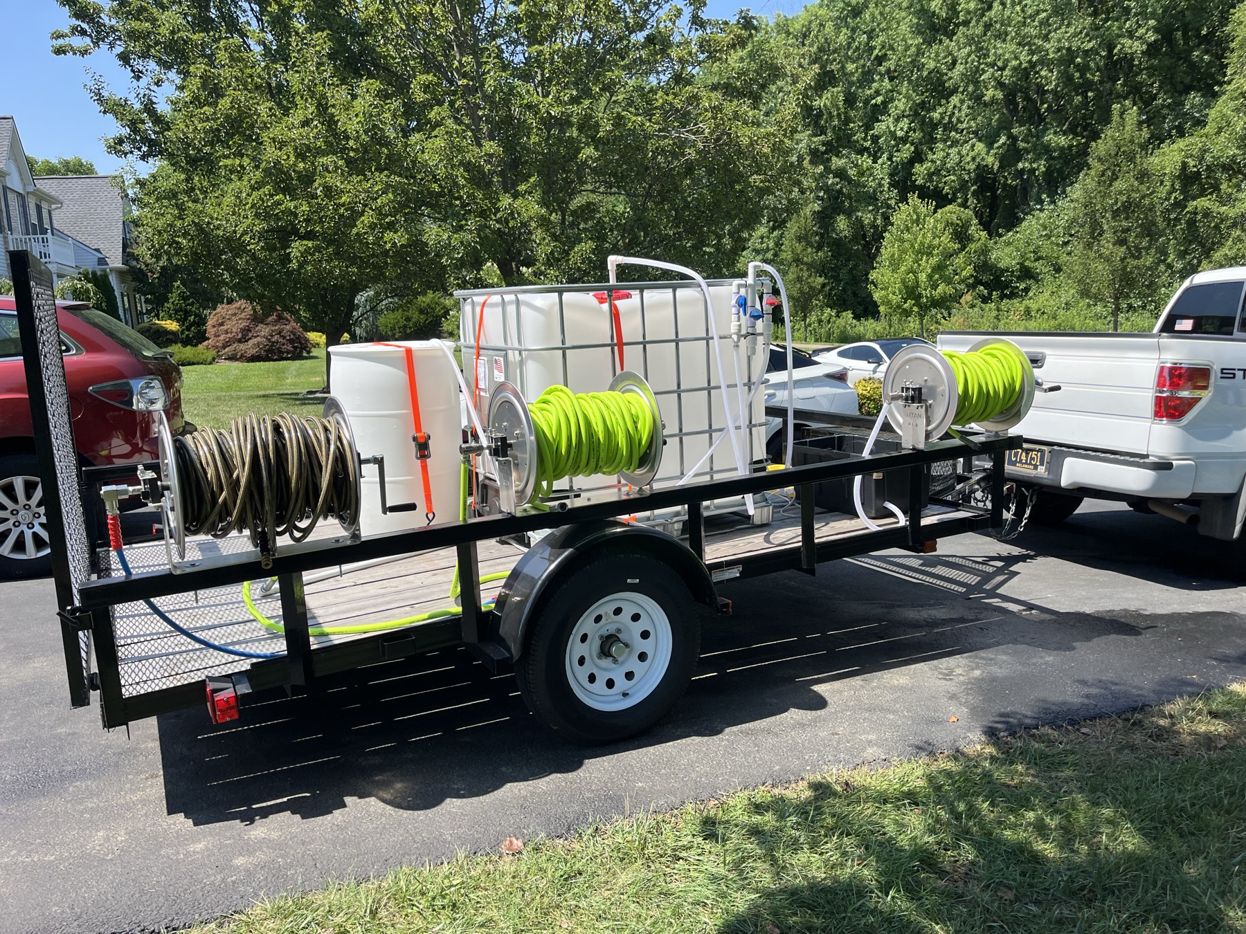 Pressure washing trailer with water tanks and high-capacity hose reels