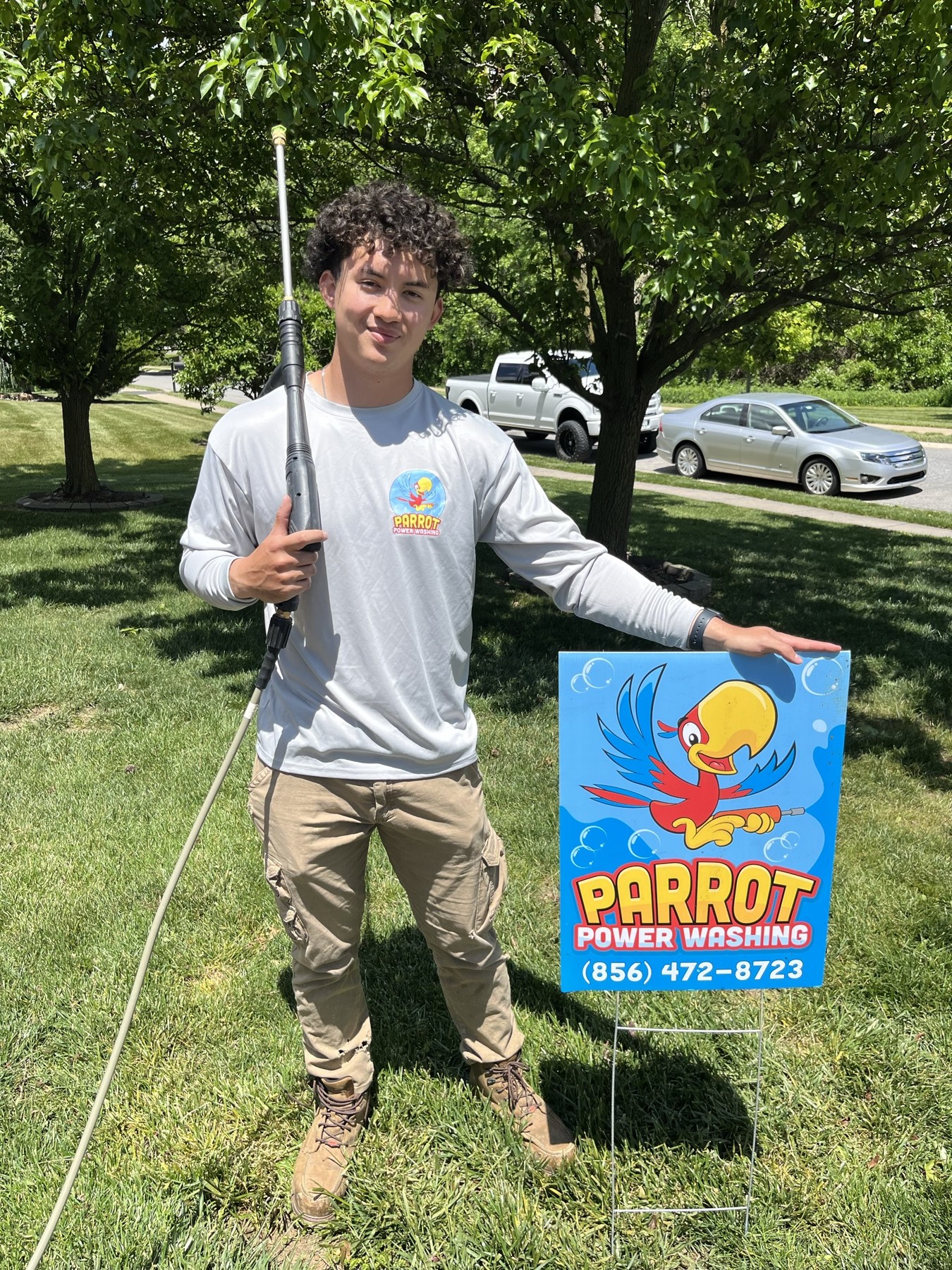 Eric, owner of Parrot Power Washing, in a branded shirt holding a pressure washing wand